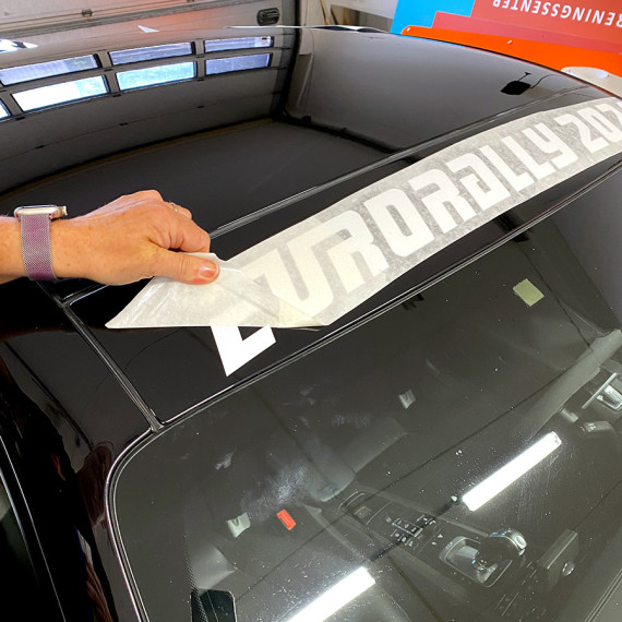 Til slutt dras påføringspapiret av logoen, og den sitter fast på bilen.